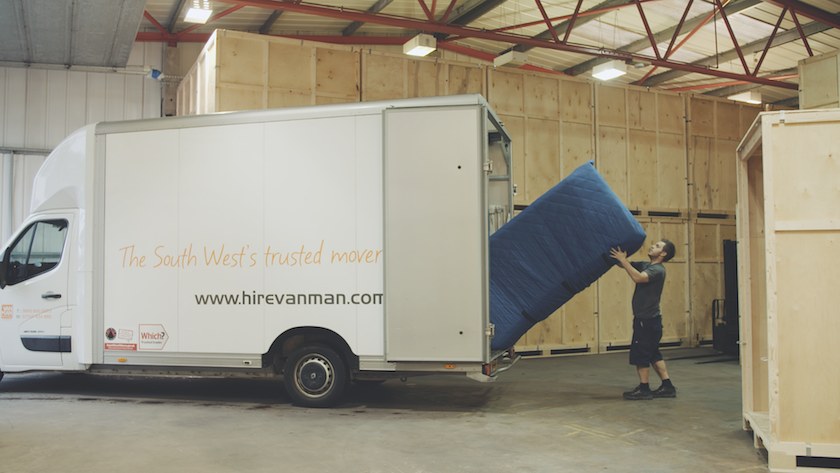 A man unloading a sofa from a van inside a storage facility